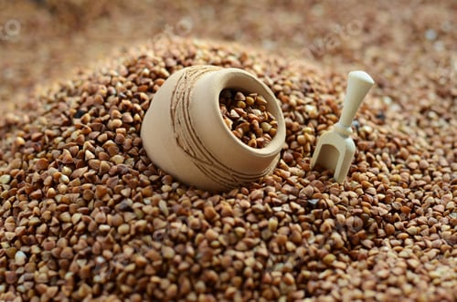 Preview: Background image of a large pile of buckwheat, in the middle of which lies a small jug an