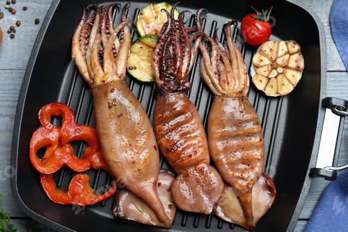 Preview: Tasty grilled squids with vegetables served on grey wooden table, flat lay