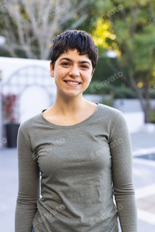 Preview: Portrait of happy biracial woman with short dark hair standing on garden terrace smiling