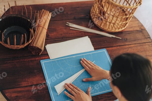 Preview: Woman twists paper tubes for weaving on wooden table