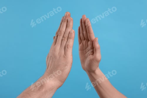 Preview: People giving high five on light blue background, closeup