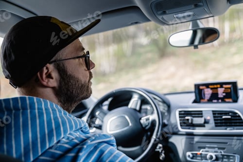 Preview: Man driving car while being on a day road trip.