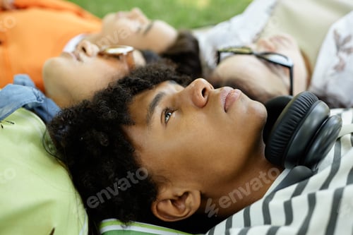 Preview: Portrait of Black Boy Lying on Grass with Friends in Park