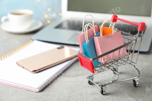 Preview: Composition with small shopping cart and paper bags on grey background, space for text