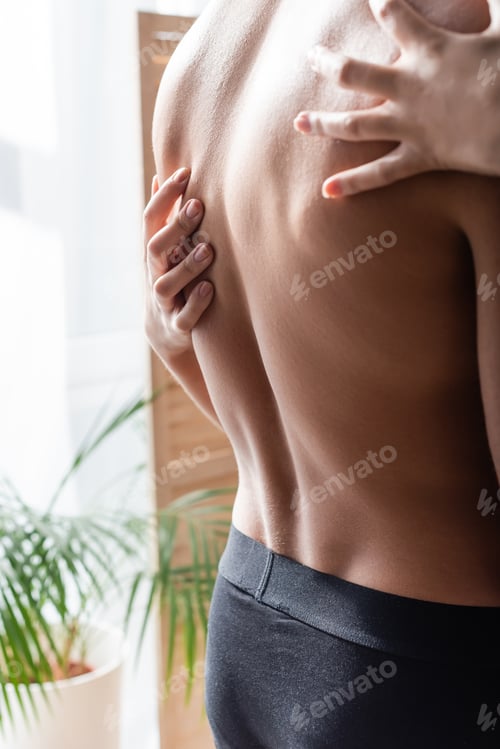 Preview: Cropped view of woman touching back of muscular man in underpants at home