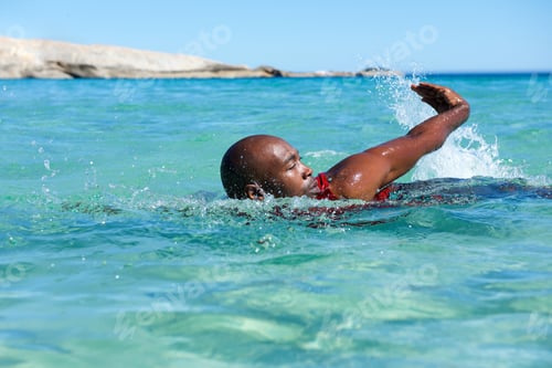 Preview: Young african man swimming in sea