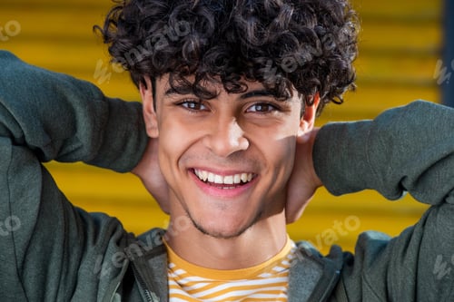Preview: Close up happy young North African man laughing with hands behind head