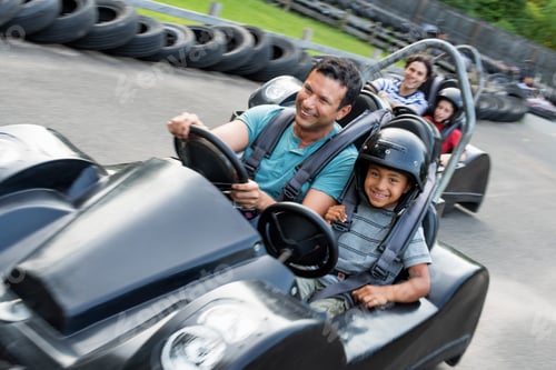 Preview: Boys and men go-karting on a track.