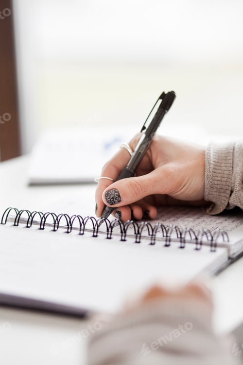 Preview: Cropped image of hand writing in spiral notebook in creative office