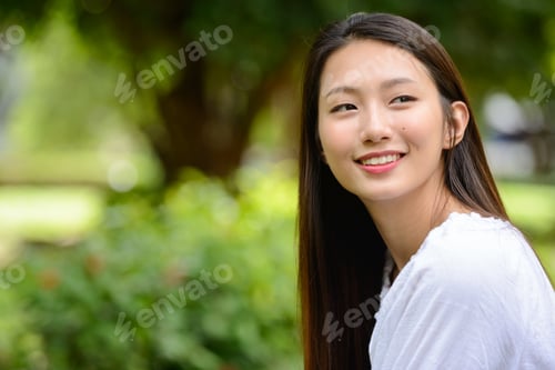 Preview: Happy young beautiful Asian teenage girl thinking at the park