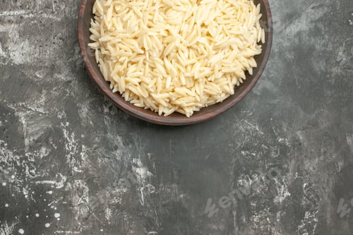 Preview: Half shot of cooked rice in a brown wooden pot on the right side on dark background