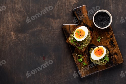 Preview: Healthy sandwich with avocado, eggs and microgreens on toast on a serving plate for breakfast. Healt