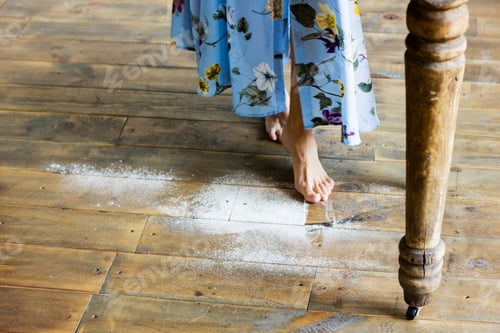 Preview: Female feet on the wooden floor of the kitchen with flour