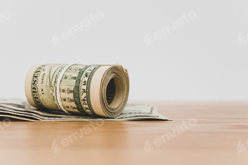 Preview: isolated US dollar banknotes roll on a wooden background with copy space