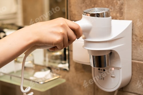 Preview: Woman takes a hair dryer with her hand in the bathroom