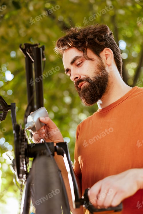 Preview: Male cyclist greasing bicycle pedal