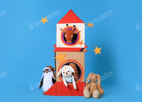 Preview: Cardboard rocket and different toys on light blue background