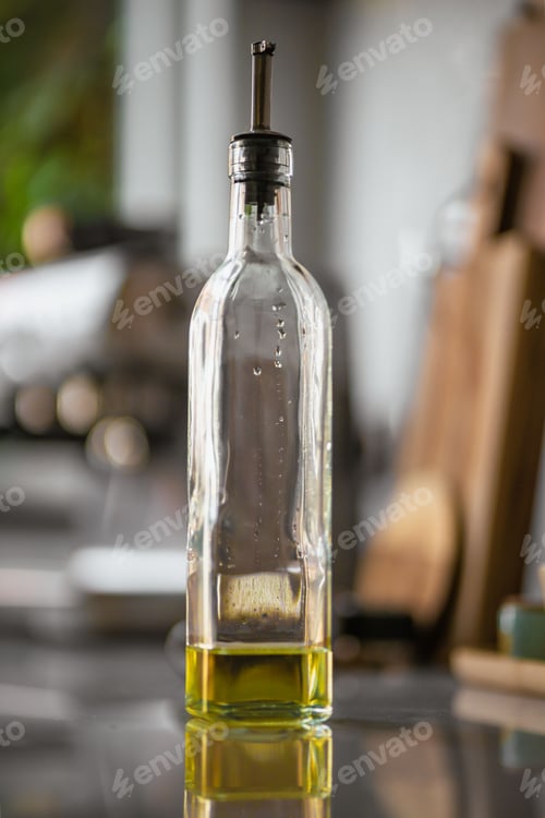 Preview: Vertical closeup of an almost empty bottle with extra virgin olive oil.