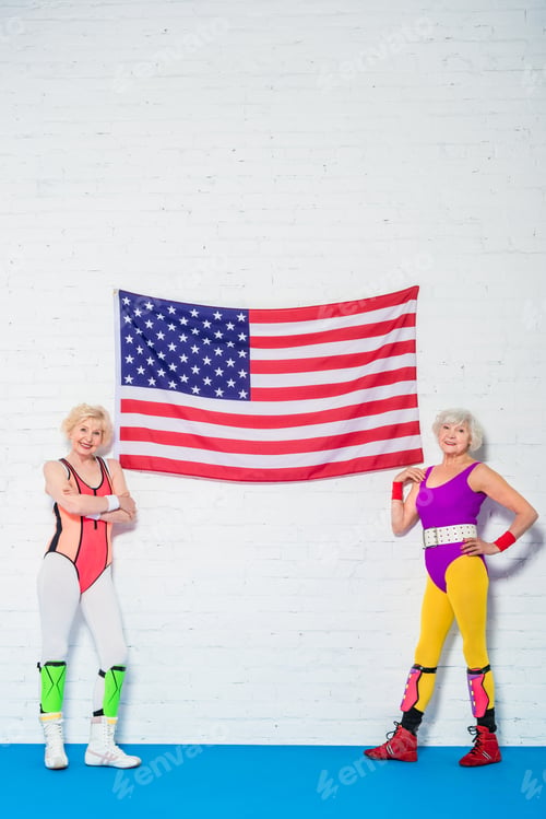Preview: full length view of beautiful senior sportswomen standing near american flag and smiling at camera