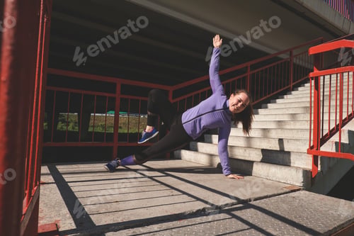 Preview: Young woman stands on one hand doing a workout. Active lifestyle concept.