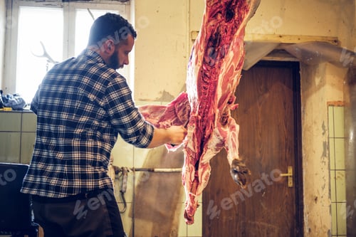 Preview: Bearded butcher cuts up the carcass of wild pig.
