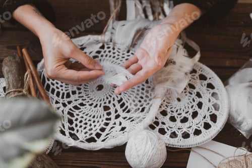Preview: young woman knitting dreamcatchers at acozy work table. hobby, craft concept
