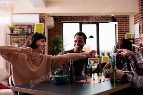 Preview: Happy playful woman acting childish while sitting with friends at home enjoying leisure activity.