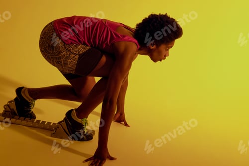 Preview: Image of african american female athlete preparing for run in neon yellow lighting