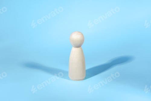 Preview: Wooden figure with two shadows on blue backdrop. Abstract concept of lonely person.