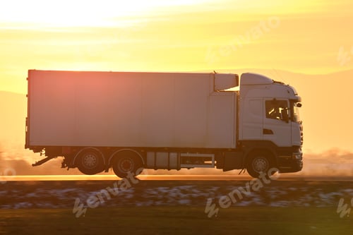 Preview: Cargo truck driving on highway hauling goods in evening.
