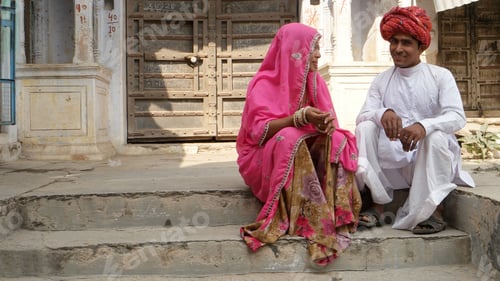 Preview: Closeup of an Indian couple in traditional outfits sitting on the stone stairs outdoors.