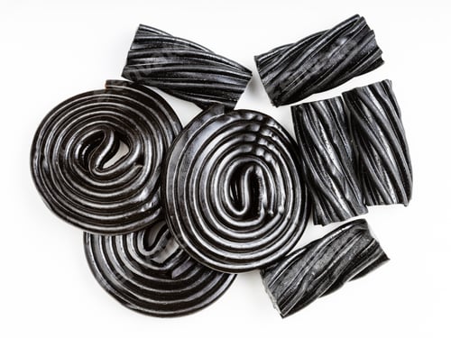 Preview: several black liquorice candies close up on white