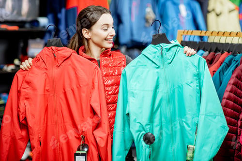 Preview: Woman choosing winter jacket in the sports shop