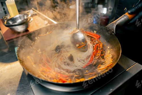 Preview: close-up of a frying pan of noodles with eggs and meat on the stove stirring almost ready to eat