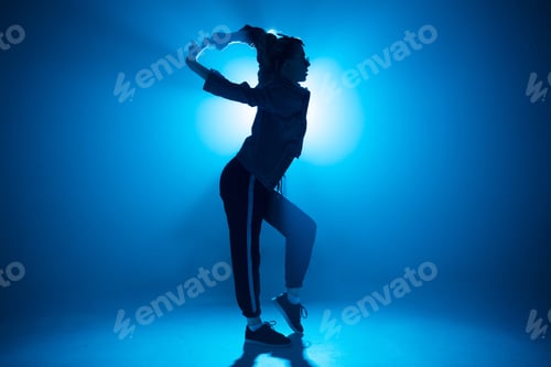 Preview: Trendy young woman dancing single in club, neon light, lots of smoke.