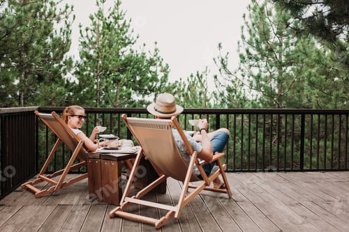 Preview: Lovely couple chilling and having a cup of coffee on sunbeds in a balcony