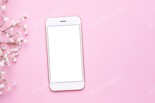 Preview: Mobile phone mock up and white flowers on pink pastel table top view in flat lay style.