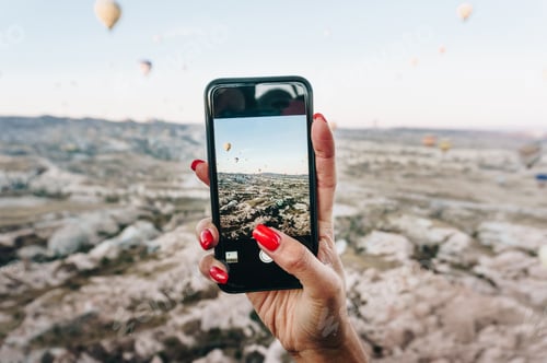 Preview: woman taking photo of Hot air balloons festival on smartphone, Cappadocia, Turkey