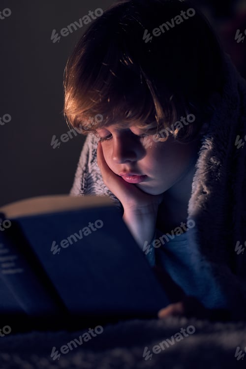 Preview: Cute boy reading boy in dark room