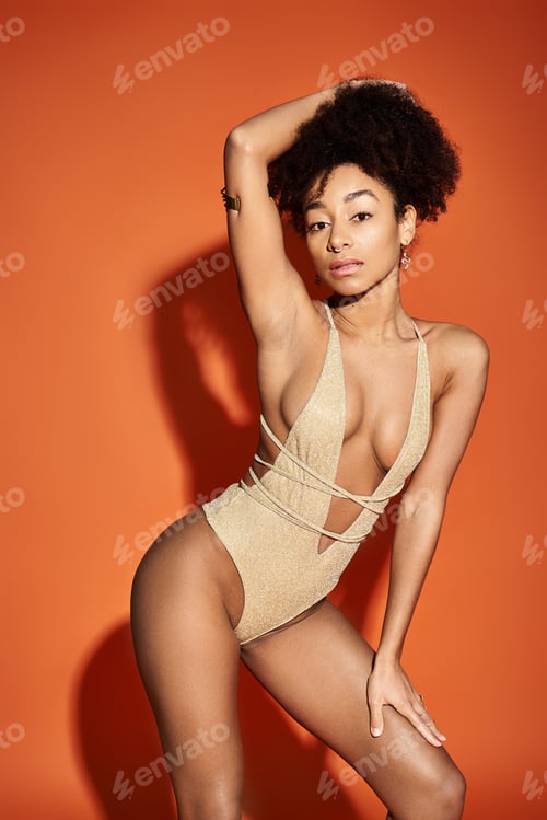Preview: Golden Goddess: Captivating Woman in Bodysuit on Vibrant Orange Background