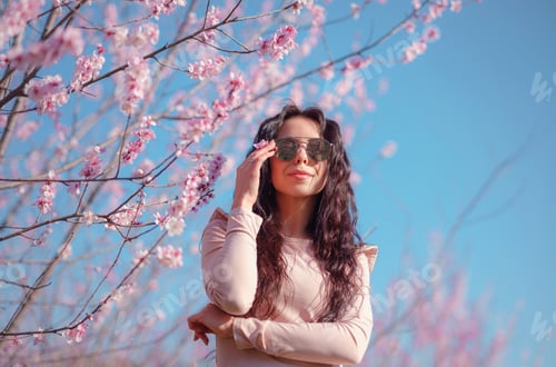 Preview: A beautiful young woman near a blooming spring pink tree
