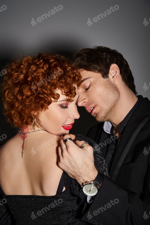 Preview: attractive sexy couple in black elegant attires kissing and hugging lovingly on gray background