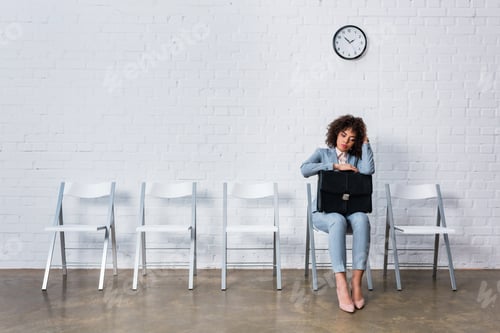 Preview: Bored woman with briefcase sitting on chair and waiting