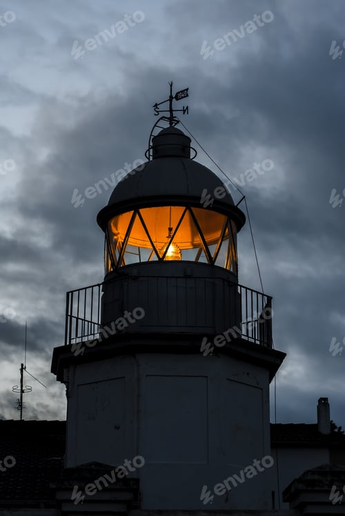 Preview: Shining lighthouse against cloudy sky