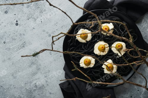 Preview: Halloween party Italian black pasta decorated horror olives like eyes on black plate on old dark tab
