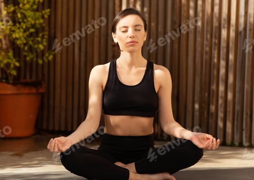 Preview: Calm relaxed millennial european woman athlete in sportswear practicing yoga in city, meditating