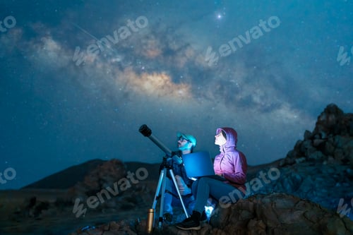 Preview: couple sitting in the desert watching the stars and Milky Way next to a telescop