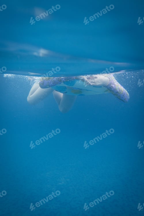 Child Swimming with Floatation Device in Blue Water