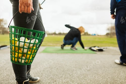 Preview: Golf practice on a cloudy day with players preparing for their shots.
