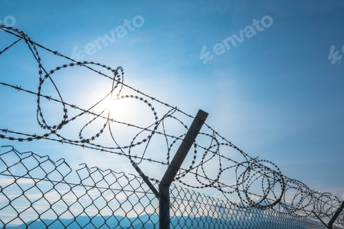 Preview: Silhouette of razor barbed wire at day.